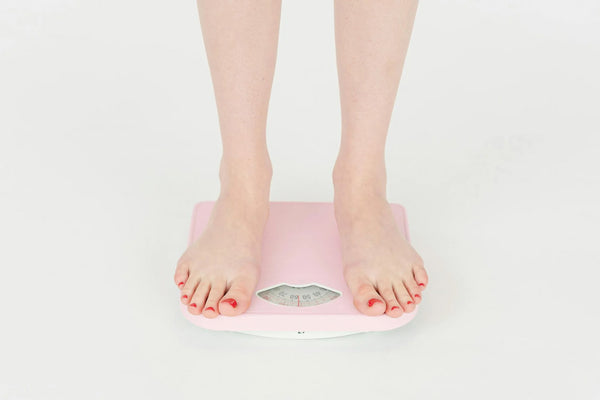 person weighing themselves on pink scales - lions mane for weight loss